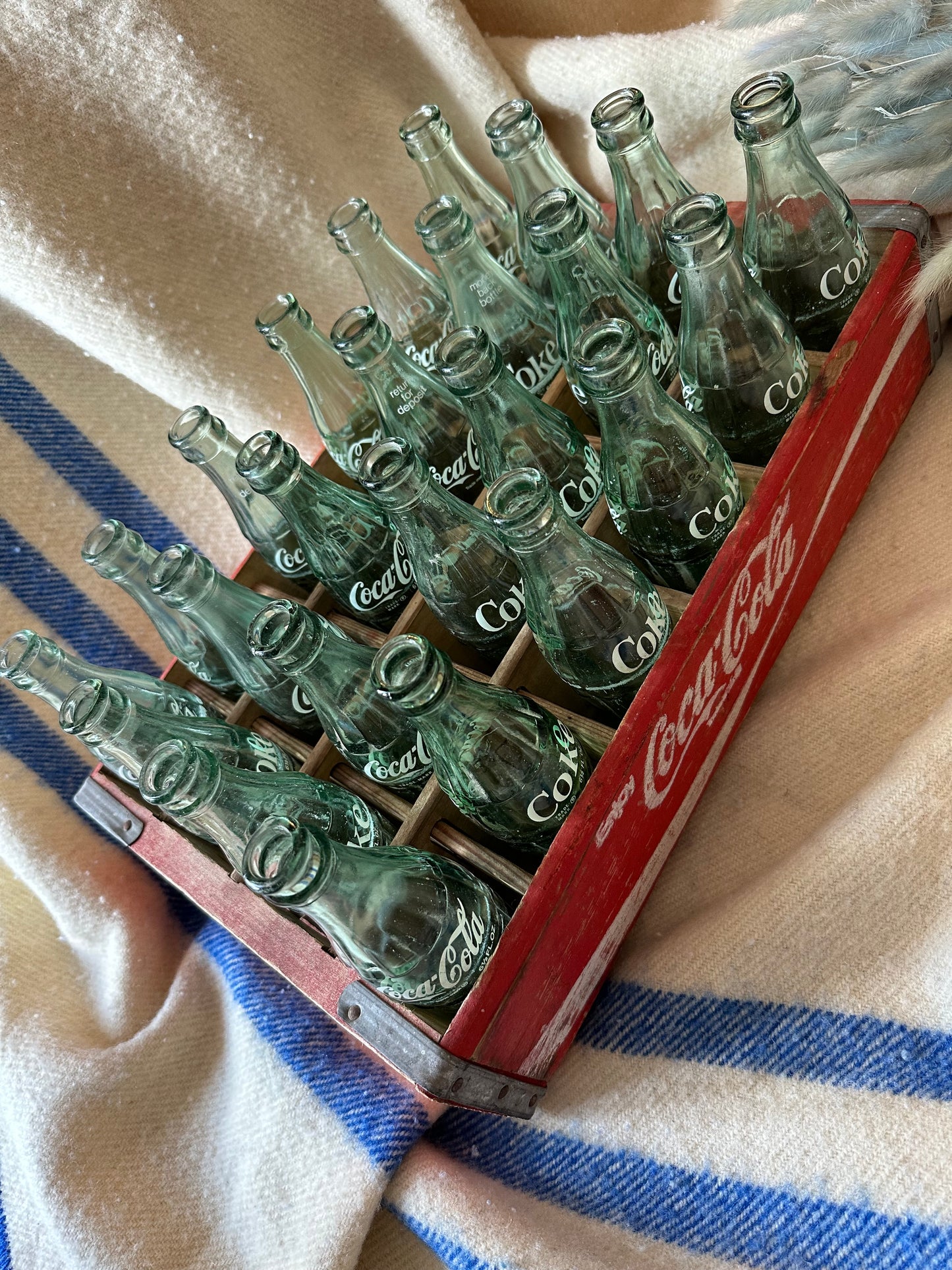 Coca Cola crate with 24 vintage Coca Cola bottles all manufactured in a different place