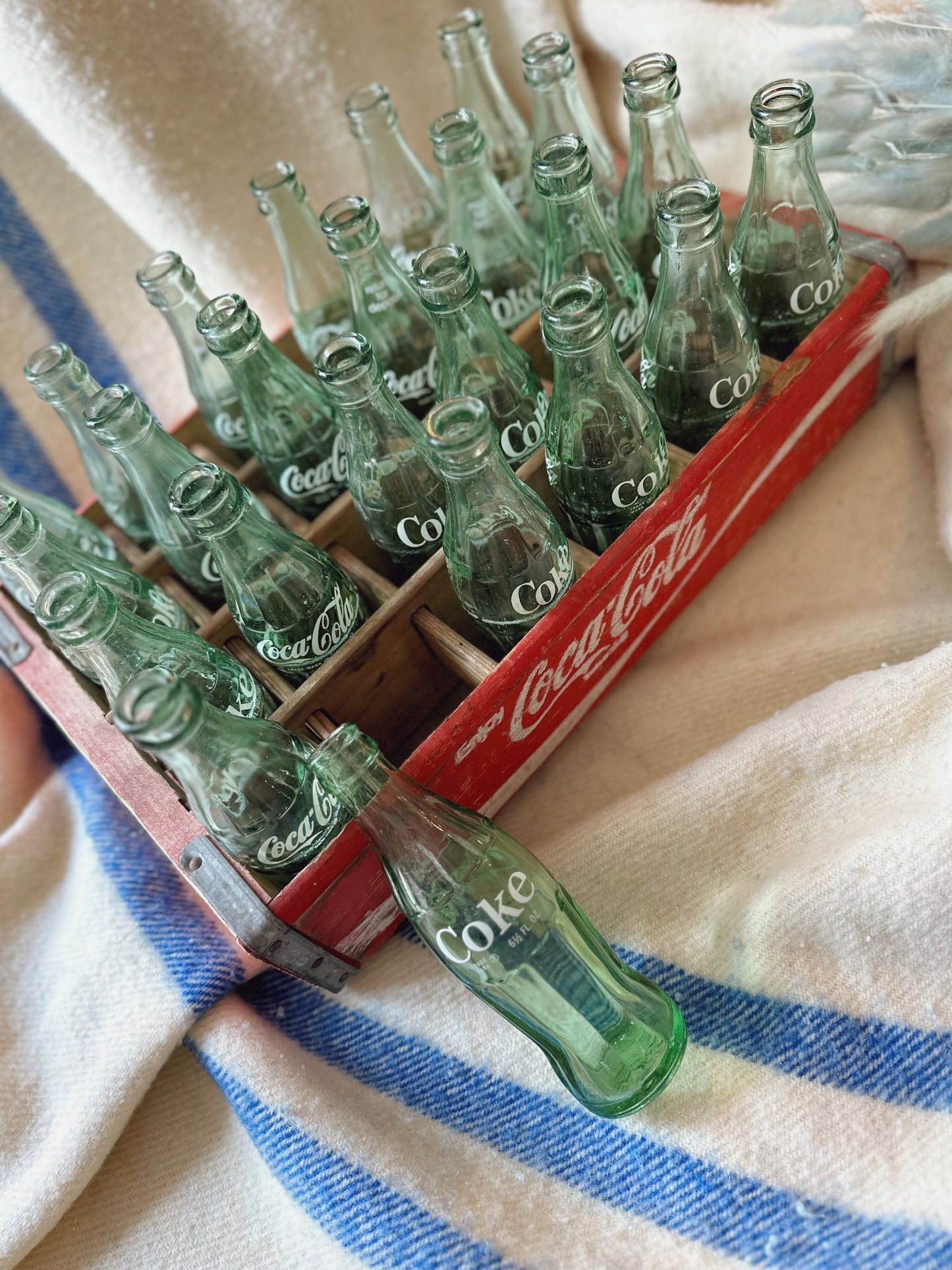 Coca Cola crate with 24 vintage Coca Cola bottles all manufactured in a different place