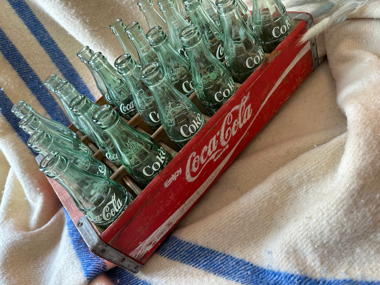 Coca Cola crate with 24 vintage Coca Cola bottles all manufactured in a different place